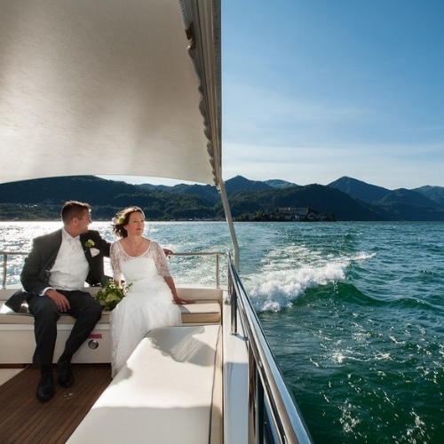 Bruidspaar op een boot op het Lago Orta Ortameer met bergen op de achtergrond.