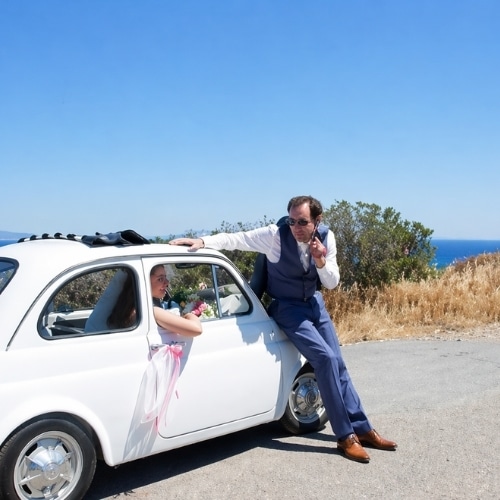 Bruidspaar bij een klassieke Fiat 500 aan de kust van Sardinië.