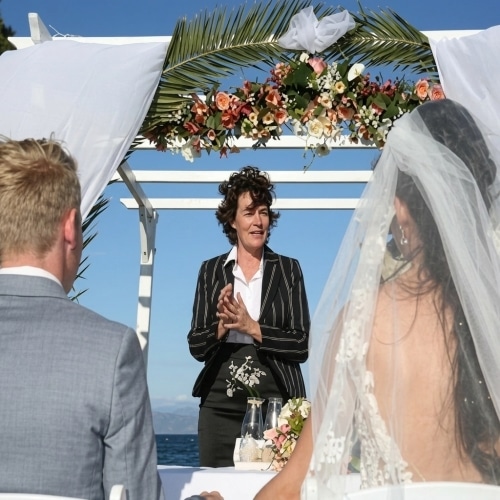 Symbolische ceremonie aan zee op Sardinië met bruidspaar en ceremoniespreker.