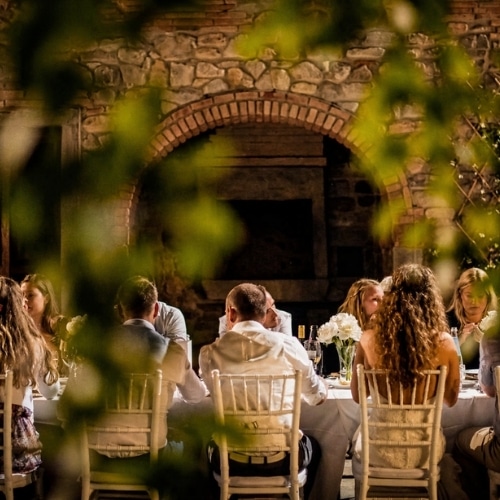 Gasten aan lange tafels tijdens een bruiloftsdiner bij een agriturismo/fattoria/wijnboerderij in Toscane.