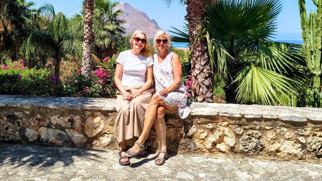 Suzanne en Miranda tijdens een bezoek aan een trouwlocatie op Sicilië, met uitzicht op zee.
