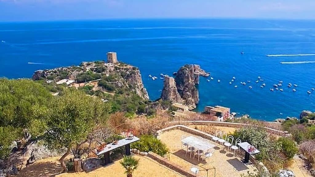 Sfeervolle trouwlocatie op Sicilië met een gedekte tafel in een mediterrane terrastuin en uitzicht op zee.
