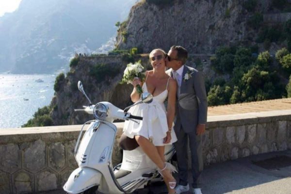 Bruidspaar op een scooter aan de kust tijdens een elopement in Italië.